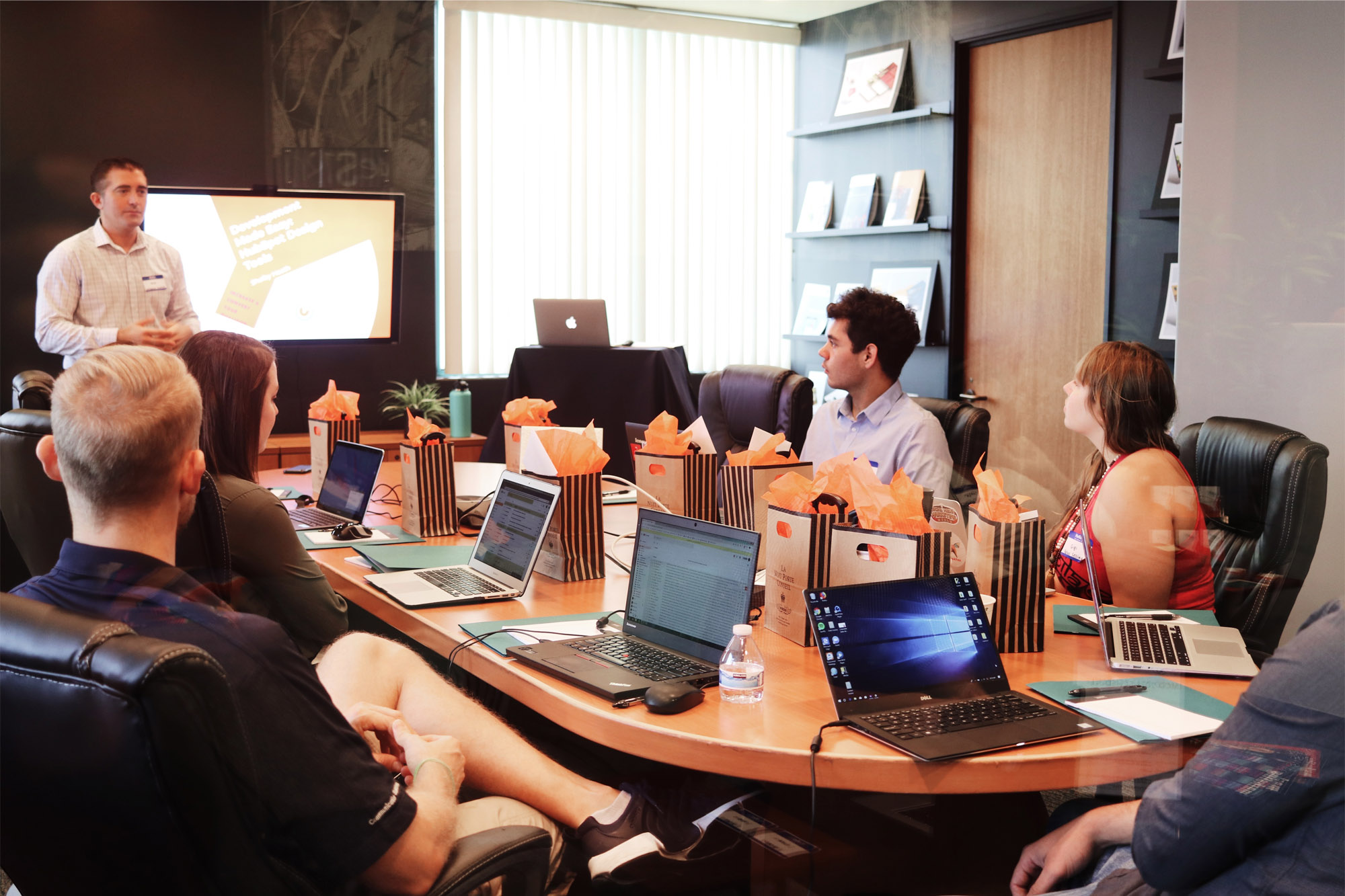 Groups of people at table with laptops being given a talk