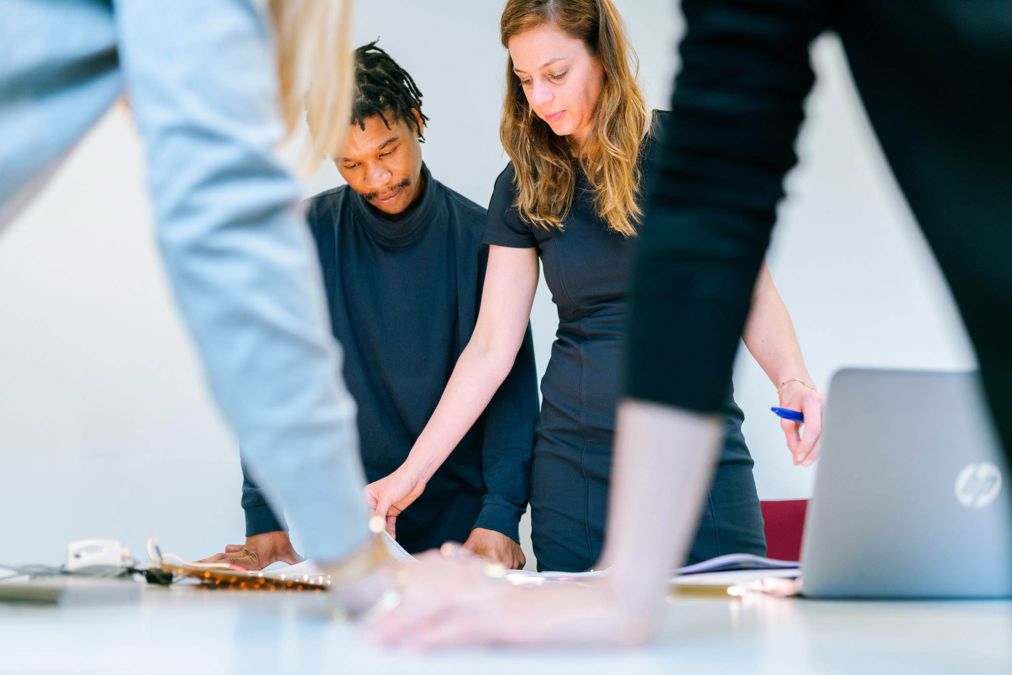 Group of people standing round table working on a problem